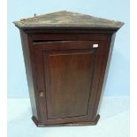 A George III oak hanging corner cupboard, the single panelled door opening to reveal two shelves.