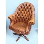 A Norwegian Ring Mekanikk swivel wing-back chair, with buttoned back, in tan leather upholstery with