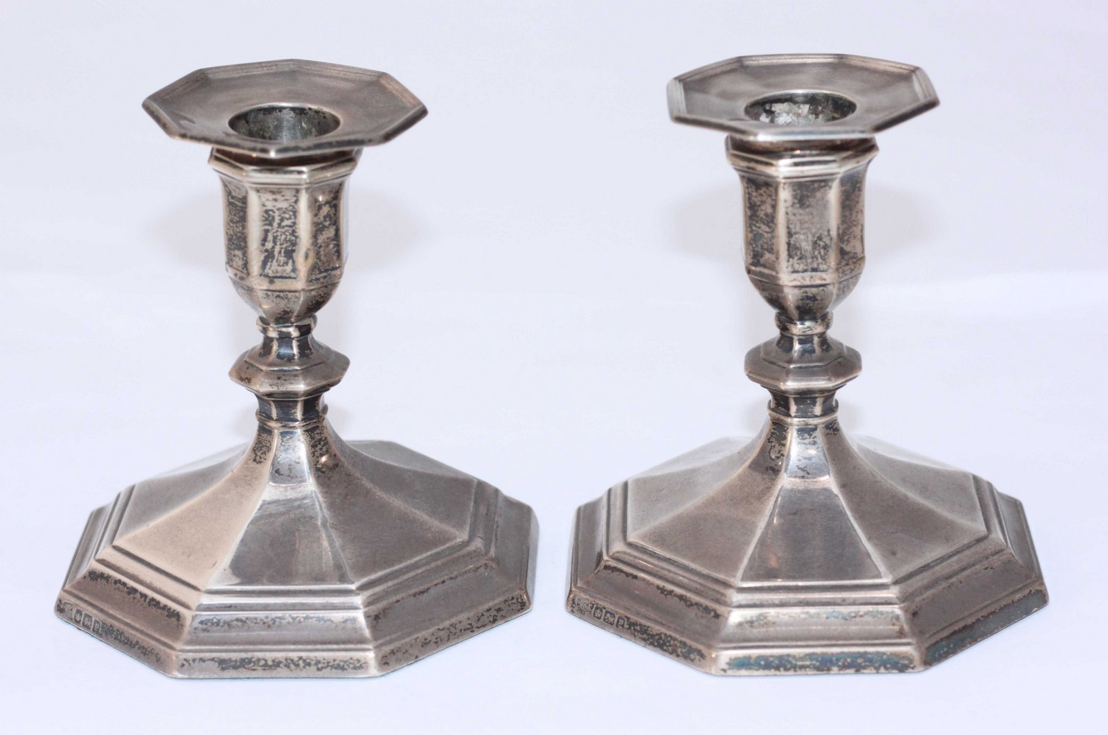 A pair of squat silver candlesticks by Hawksworth Eyre & Co. Ltd, with splayed, octagonal loaded