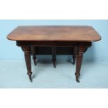 A large Victorian mahogany drop-leaf dining table, with rounded ends on heavily fluted supports to