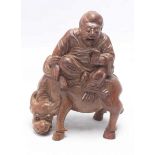 A Chinese carved bamboo figure of a Buddhist figure seated on a buffalo, 19cm high