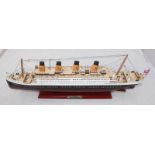 A painted wooden model of RMS Titanic on painted stand, approximately 55cm long, together with a