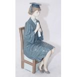 A Lladro porcelain figure of a seated female graduate with mortarboard and scroll. 26cm high.