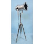 An industrial style, chrome studio/stage light raised on extendable tripod base.