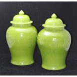 A pair of pea-green glazed Chinese temple jars with covers and marks to base, slight chip to one