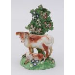 An 18th century Derby porcelain figure group of a cow and calf beneath a floral bocage. 15cm high.