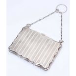 A silver and leather lined purse, of rectangular form with serpentine edges, engine turned