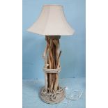 A floor standing lamp, with cream shade, raised on a support constructed from multiple sticks and