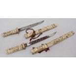 Two Japanese daggers with bone handles and scabbards carved with various figures, the blades 8" &