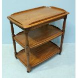 An Ercol light elm three-tier trolley, raised on turned supports to castors. 80cm.