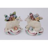 A pair of porcelain figures in the Chelsea style, modelled as recumbent sheep lying next to floral