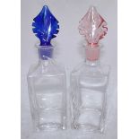 A pair of glass decanters with coloured blue and pink glass stoppers