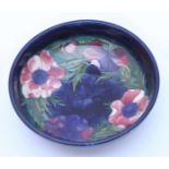 A Moorcroft pottery bowl in the 'Anemone' pattern painted to a dark blue ground, 'WM' monogram