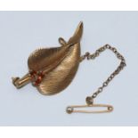 A 9ct gold brooch modelled as a leaf, set with three small garnet coloured stones, with safety pin