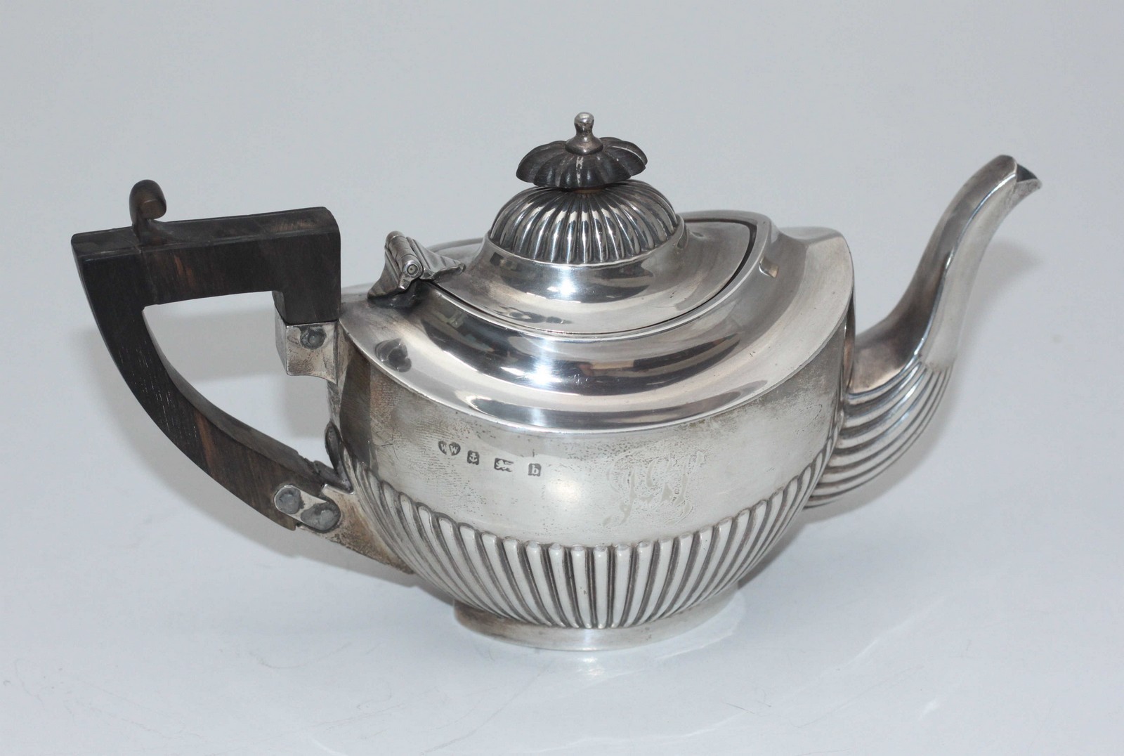 A silver teapot with half-gadrooned body, ebonised handle and finial, Birmingham, 1901, maker's mark