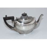 A silver teapot with half-gadrooned body, ebonised handle and finial, Birmingham, 1901, maker's mark