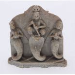 An Indian carved soapstone figure-group depicting a central figure crouched atop a snake holding a