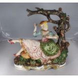 A large Capodimonte figure of a lady sat beneath a tree, raised on platform base with gilt scrolling