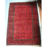 A hand-knotted Baluchistan rug of rectangular form, decorated with blue stylized guls to a red