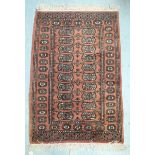 A small hand-knotted tufted carpet of Caucasian design with stylised guls to a rust-coloured
