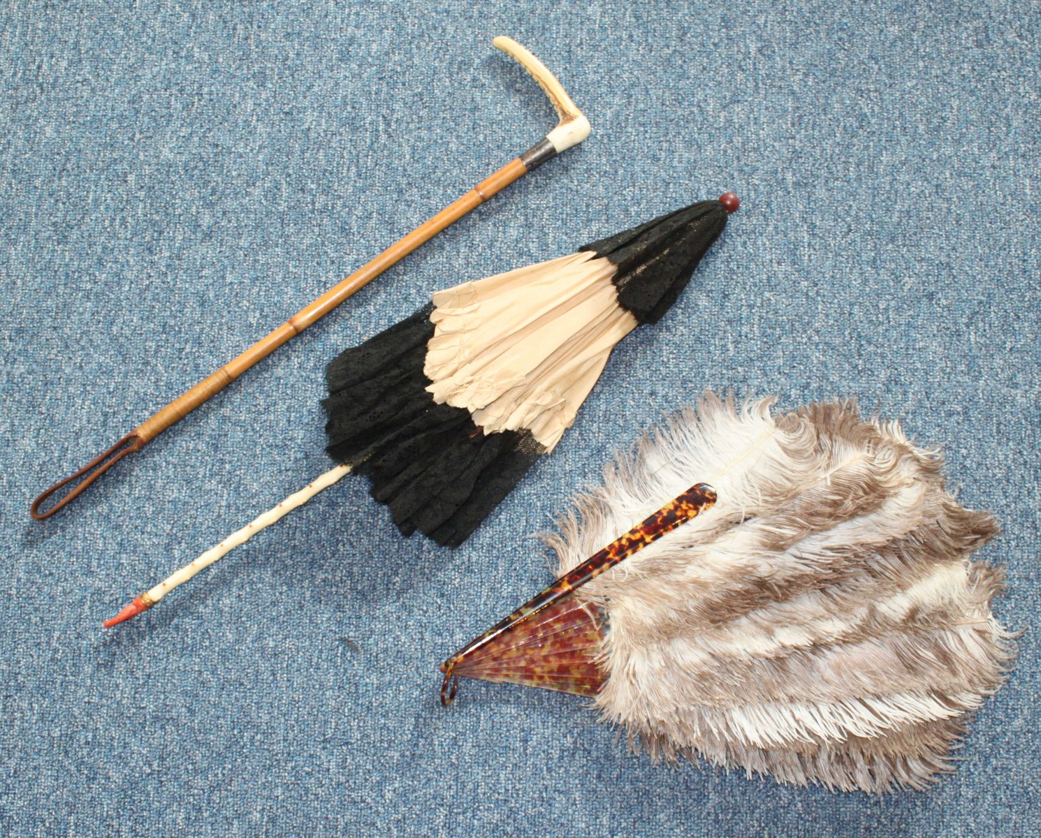 A late 19th/ early 20th century black lace and white silk parasol with carved ivory and coral