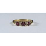 An 18ct gold ring, the top set with three ruby coloured stones and four small diamonds. Ring size '