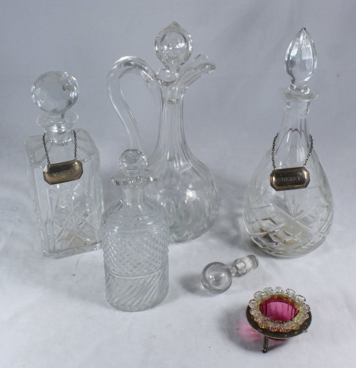 Four various cut glass decanters, two with silver bottle tags together with a cranberry glass