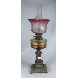 A Victorian brass oil lamp with cranberry-tinted and etched shade glass reservoir, 65cm high
