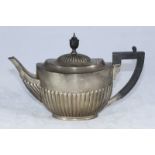 An early 20th silver teapot of oval form with half-reeded body, ebonised finial and handle,