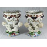 A pair of Continental porcelain vases, each modelled as three merbabies supporting a vase, on