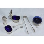A silver condiment set comprising salt, pepper and mustard, blue glass liners and silver spoons