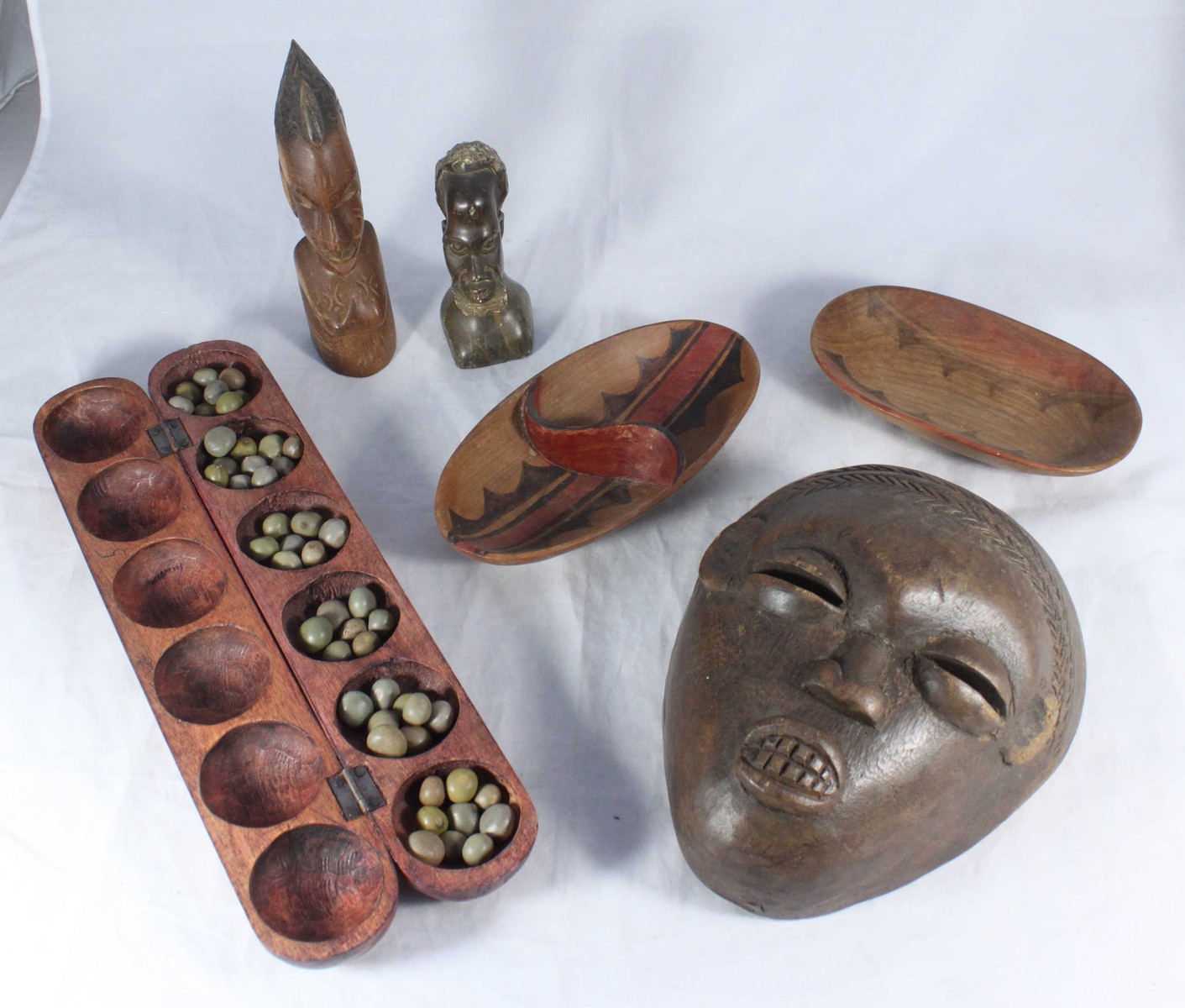 An African Ovimbundu tribal mask, together with an African carved Wuri game, a stone carved bust