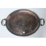 A large silver-plated two handled oval tray with carved decoration, raised on shaped feet. 76cm long