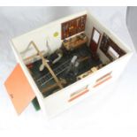 A dolls house modelled as a fully-fitted workshop with removable top, a garage door, windows and