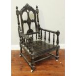An ebonised carved wood carver chair, with floral and pierced carved back, raised on turned supports