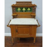 A 19th century oak washstand with tiled back-splash and marble top, above a single panelled door and