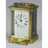 A brass carriage clock with exposed platform escapement, the white enamel dial with Roman numerals