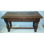 A Jacobean style carved oak table, raised on cup and cover supports and with central stretcher.