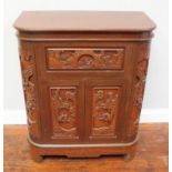 An ornately carved Oriental hardwood cocktail cabinet, with central pull-down flap, above two