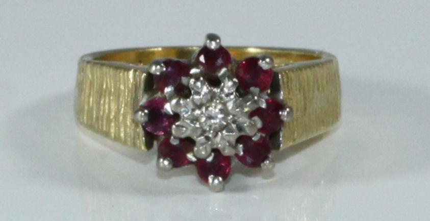 An 18ct gold, ruby and diamond ring, textured shank, illusion-set diamond surrounded by eight