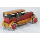 A lithographed tinplate clockwork 1920s car with driver, printed in orange and red and the tyres