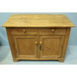 A pine cupboard with two short frieze drawers above two panelled cupboard doors enclosing shelf,