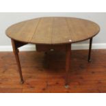An 18th century oak oval gate-leg, drop-leaf dining table with turned and tapering supports to pad