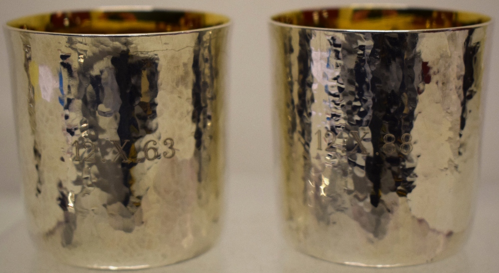 A pair of modern design Britannia standard silver beakers, the hammered finish engraved with 25th