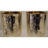 A pair of modern design Britannia standard silver beakers, the hammered finish engraved with 25th