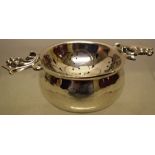 R E Stone. A modern movement silver tea strainer, with two leaf and berry cast handles, on a wrought