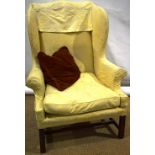 A George III wing armchair, with a cushion seat, on mahogany square legs, with an 'H' stretcher.