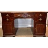 An early nineteenth century mahogany veneered partners kneehole desk, the front and back each with