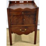 A George III mahogany bedside cupboard, with a pierced gallery above a drawer and a pair of doors,