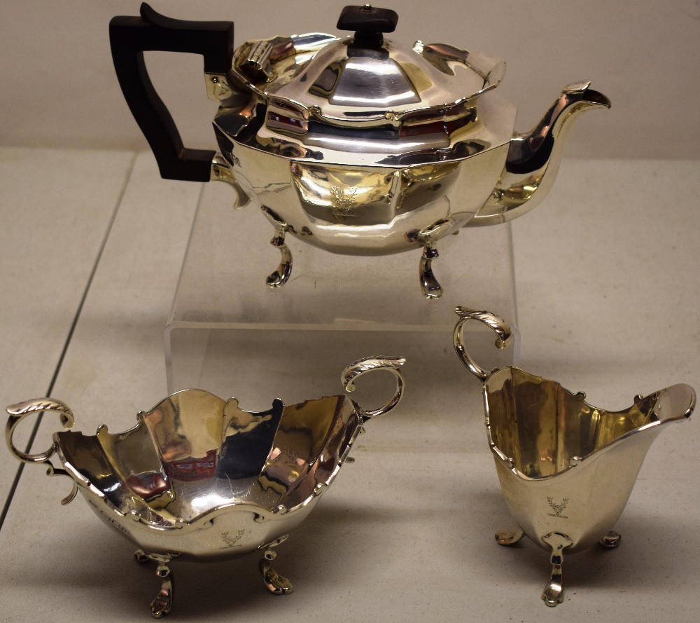 A small oval silver three piece tea service, the panelled sides engraved a stags head crest, the